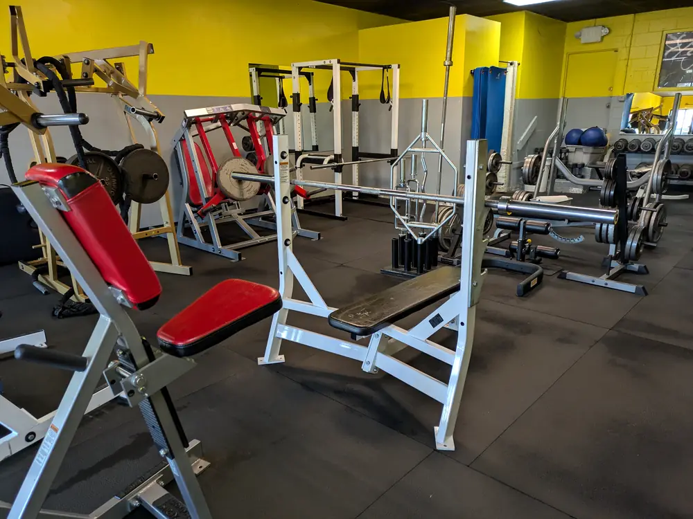 Gym with weight benches and machines on a clean rubber floor