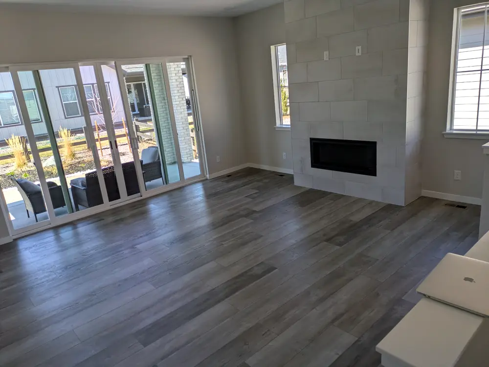 Empty living room with new plank floors, sliding doors and a tiled fireplace after a post-construction clean