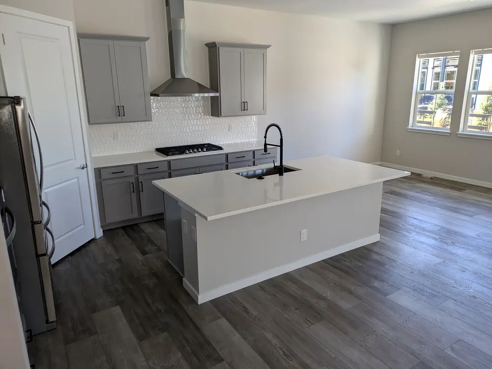 Empty kitchen with a white island and grey cabinets, cleaned for a move-in
