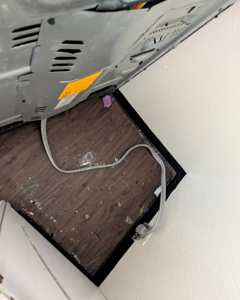 Floor under a pulled-out stove covered in grime and debris before a move-out clean
