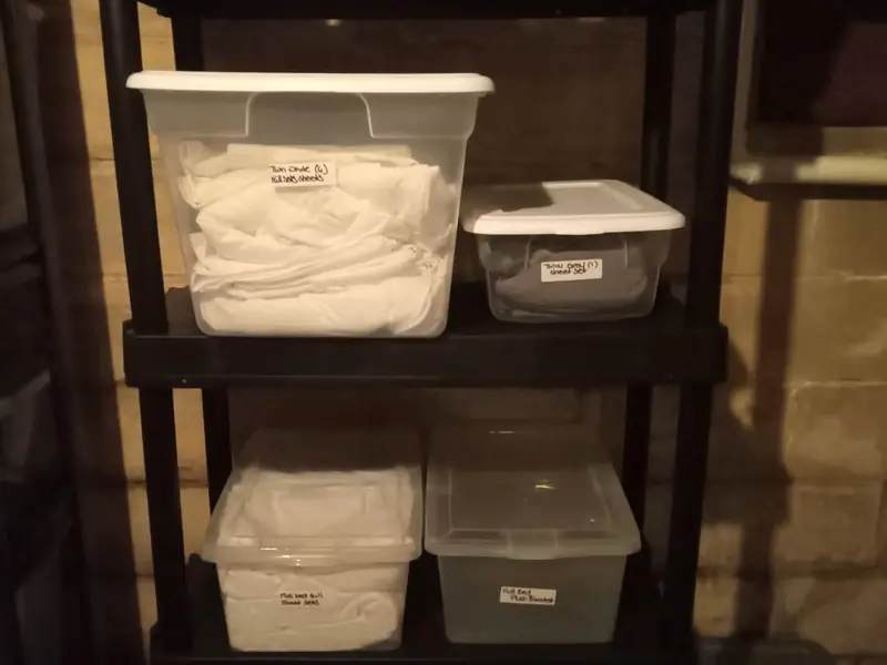 Shelf of clear storage bins with handwritten labels