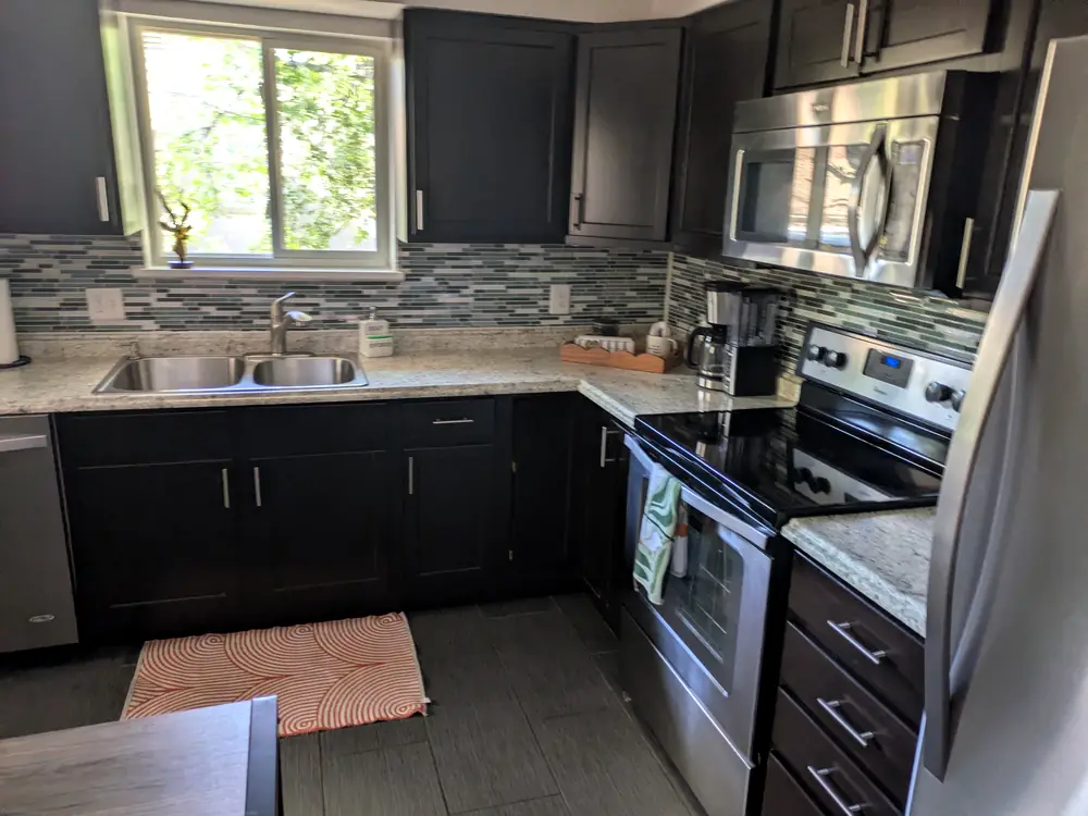 Kitchen with dark cabinets, a tiled backsplash and stainless range after a clean