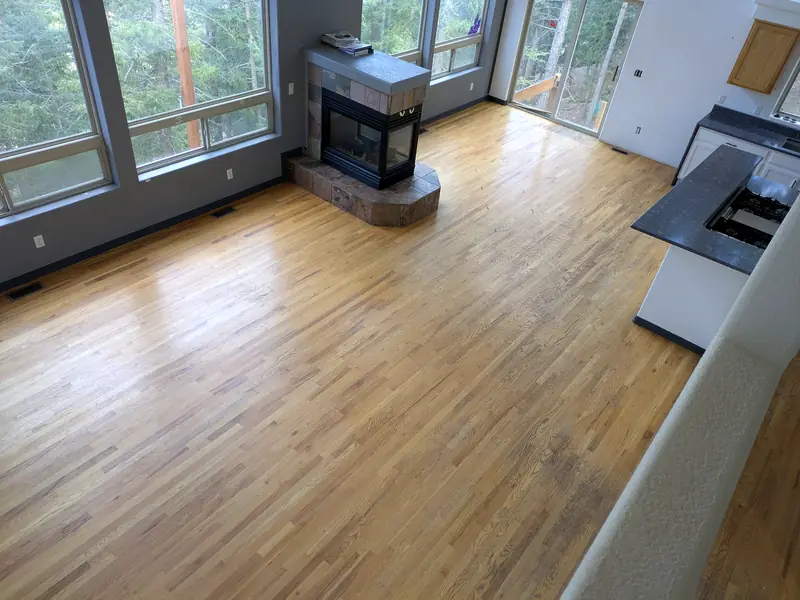 Hardwood floor in an empty room with a corner fireplace, cleaned and polished