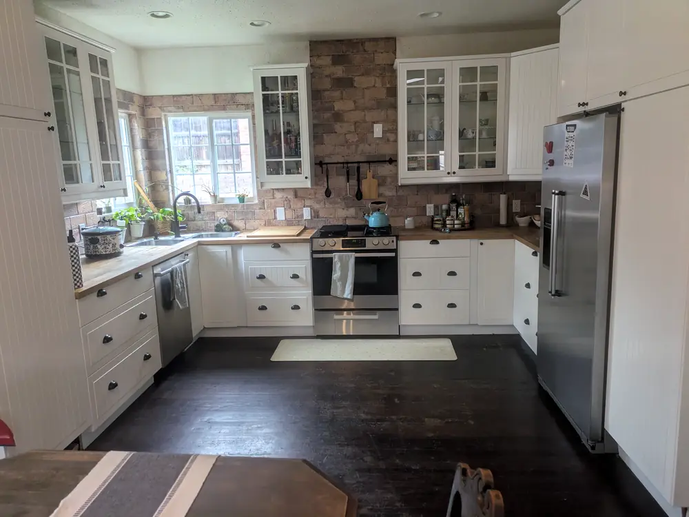 White kitchen with glass-front cabinets and a brick backsplash after a clean