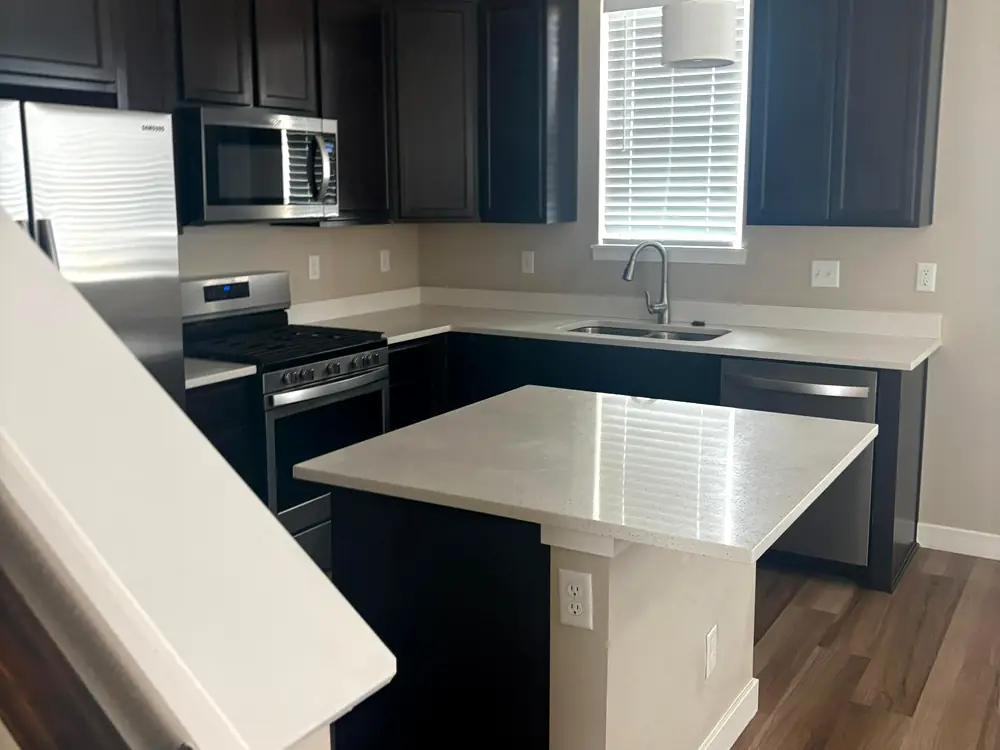 Kitchen with dark cabinets and a white quartz island after a clean