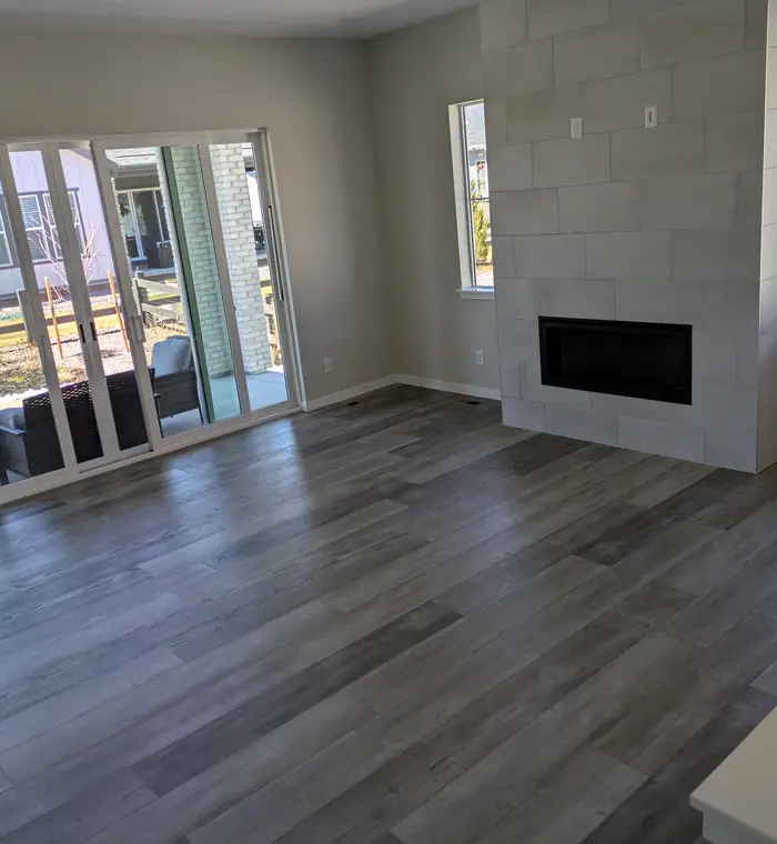 Empty living room with new floors and a fireplace after a post-construction clean