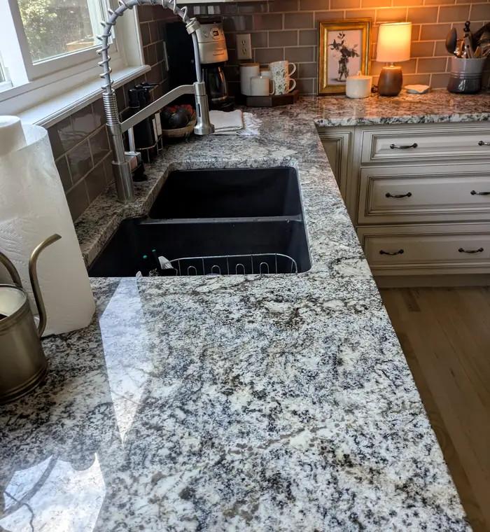 Granite kitchen counter and sink wiped down during a deep clean